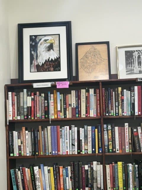 Shelves of secondhand books inside the Book Barn, with a framed painting of a bald eagle and a framed historic county map standing on top.